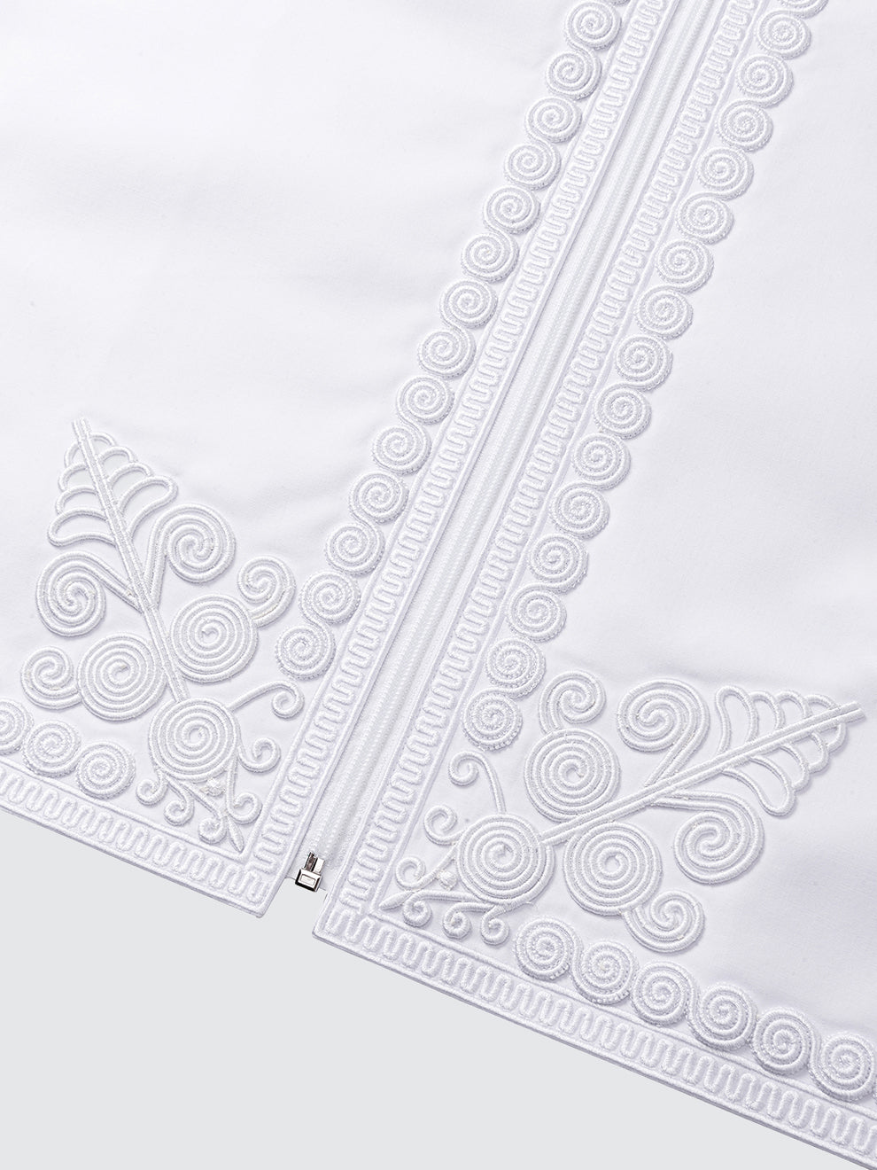Close up of imperial Moroccan waistcoat embroidery in white, showcasing intricate patterns and high end traditional craftsmanship
