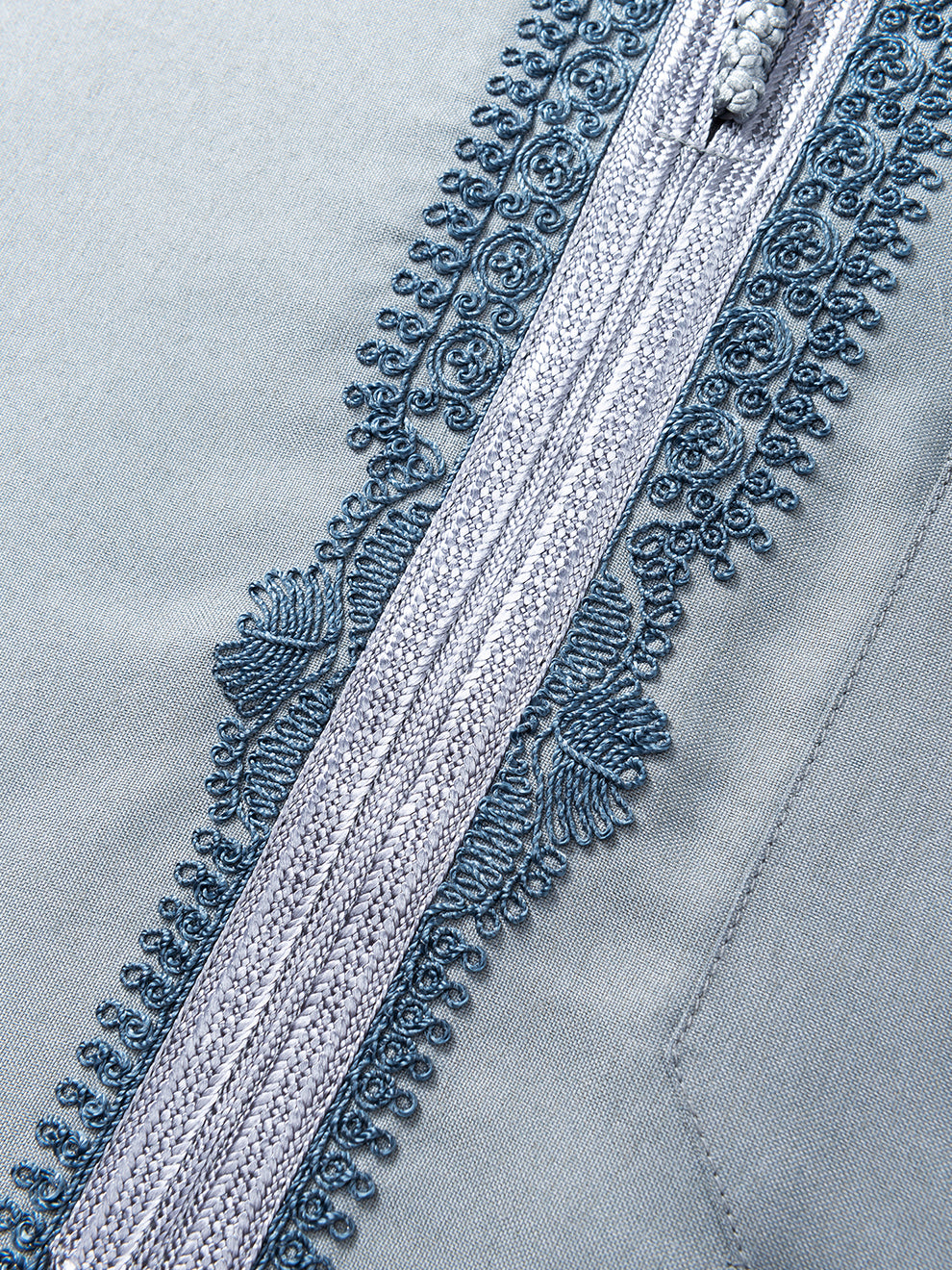 Detailed view of blue embroidered placket and chest pocket on slate blue Moroccan long sleeve thobe by Imaarah