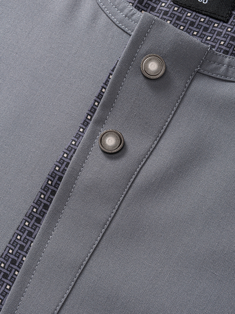 Close-up of Imaarah Vantage grey short sleeve thobe buttons and textured fabric detail